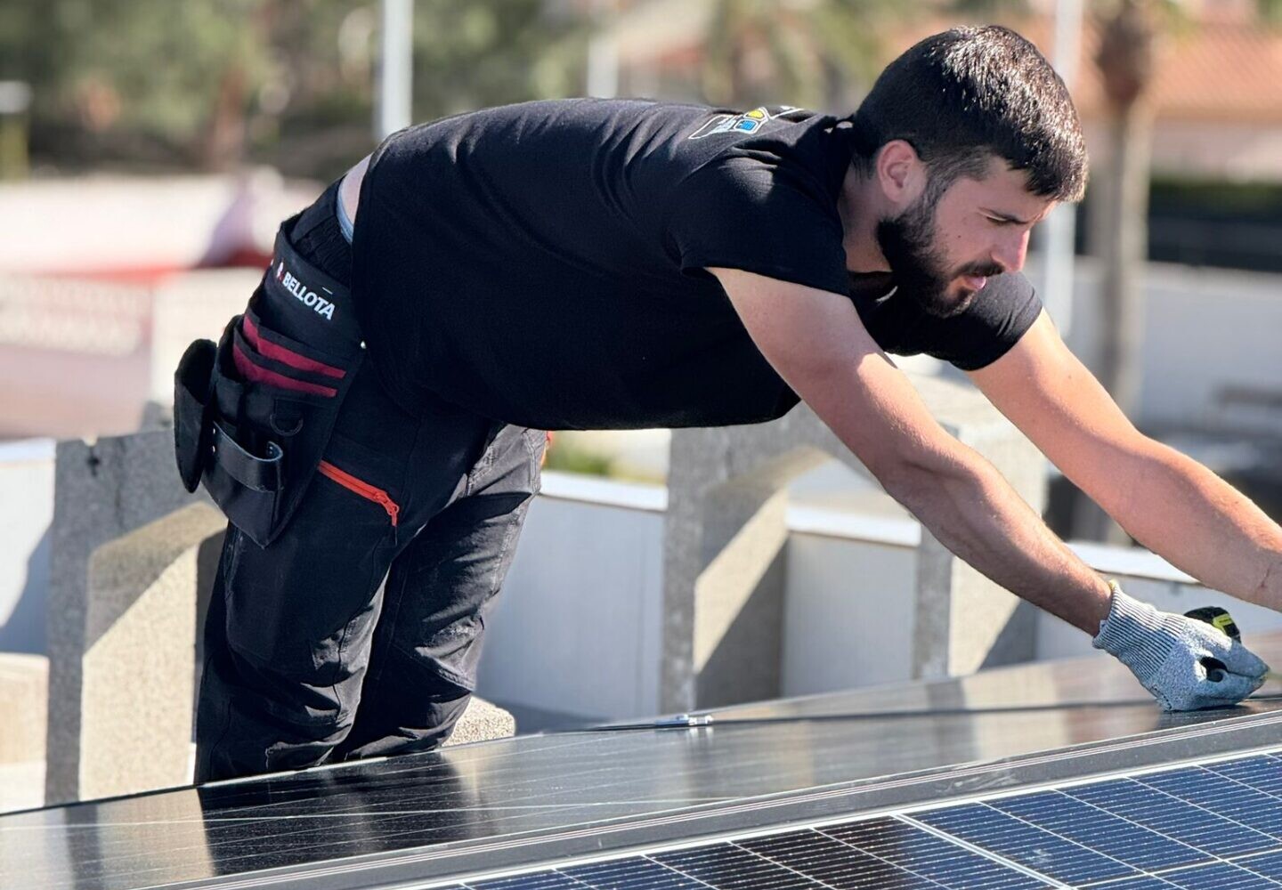 Tecnico con guantes realizando mantenimiento de paneles solares en tejado de vivienda